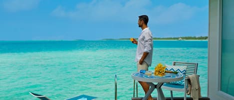 Un hombre de pie junto a una mesa con vistas a aguas turquesas.