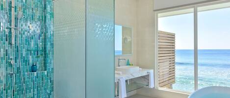 Un baño moderno con cabina de ducha de vidrio, una bañera grande y vistas al océano.