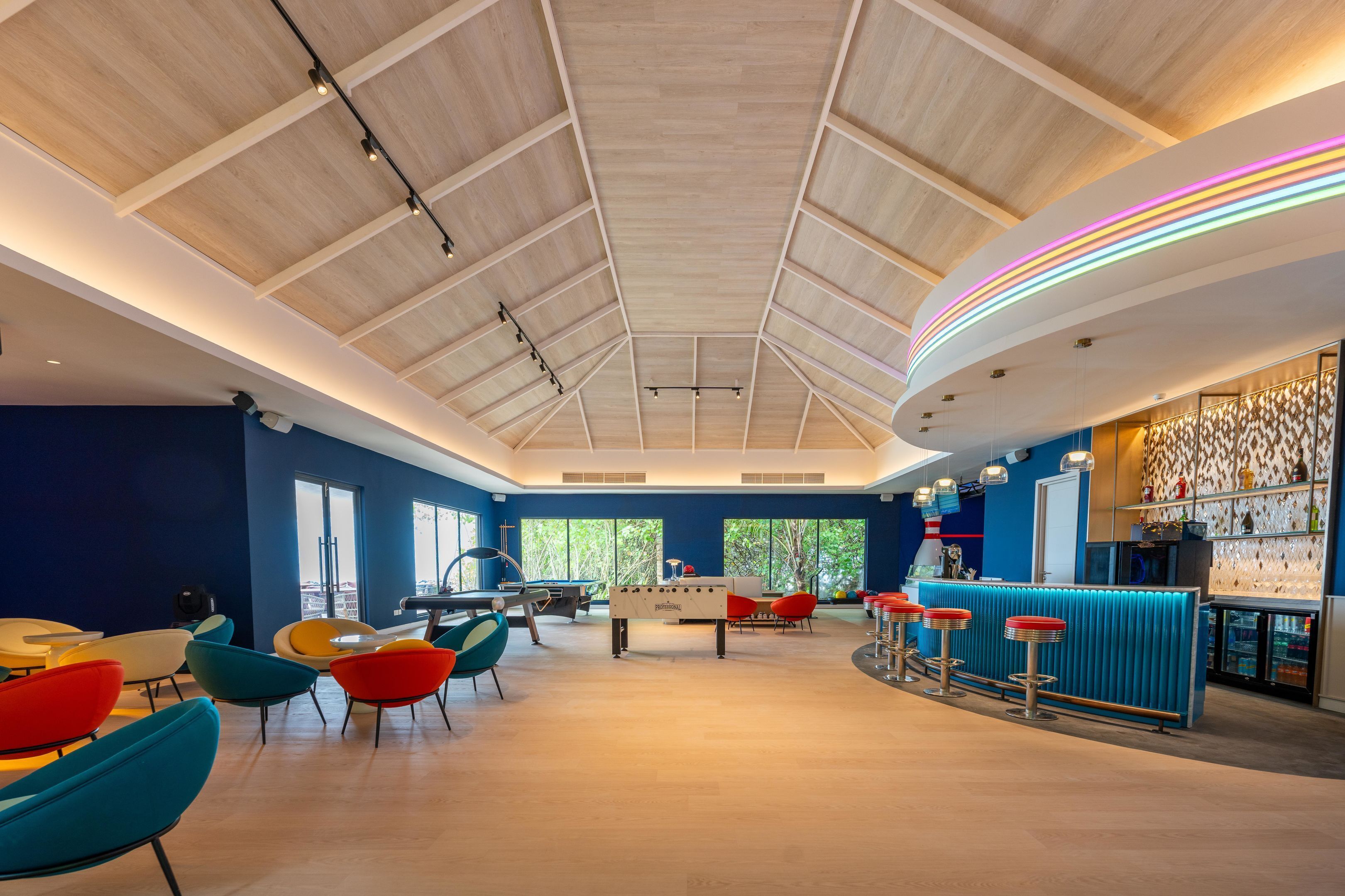 A spacious room with a pool table, foosball table, and colorful chairs.