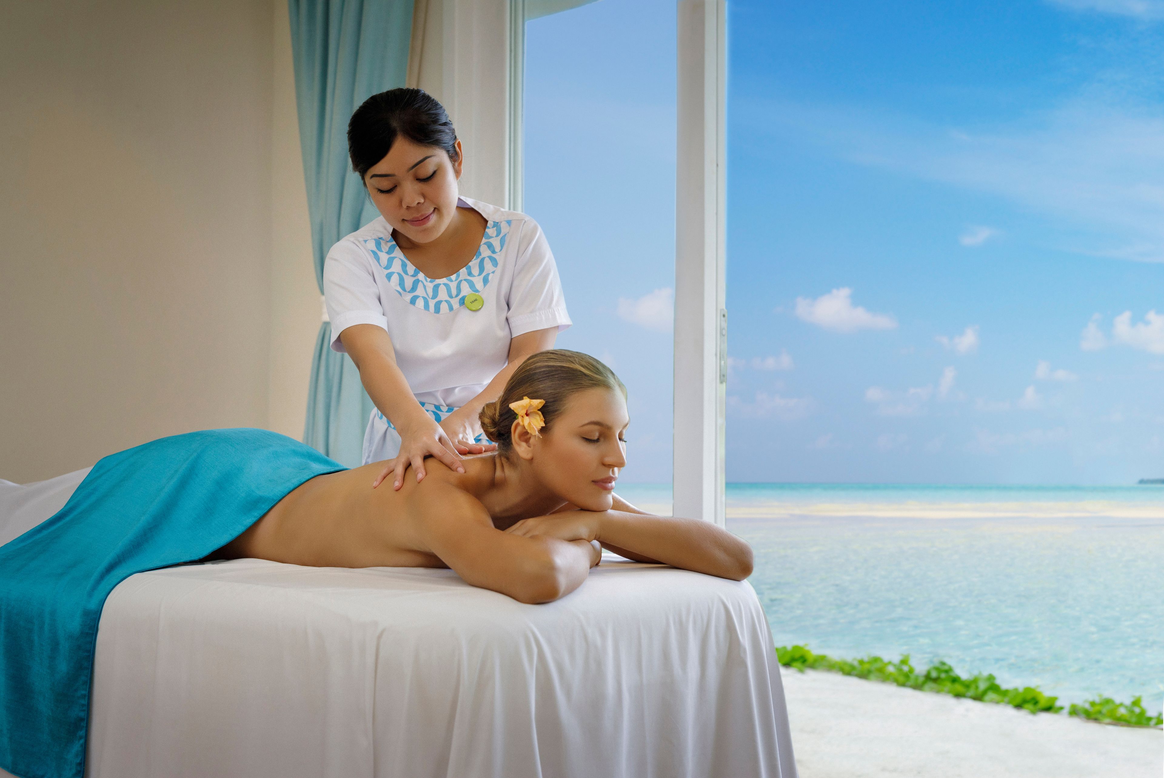 A massage therapy session on a bed with a view of the ocean.