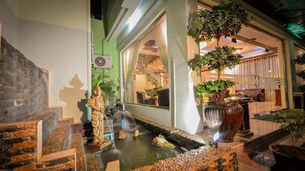 A traditional Japanese-style interior with a stone water feature, a Buddha statue, and a modern staircase. - Hotel Wonderland (Mandalay)