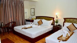 A hotel room with two beds, wooden headboards, a desk, and a chair. - Hotel Wonderland (Mandalay)