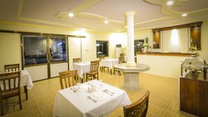 A restaurant with tables set for dining, a central column, and a buffet area. - Hotel Wonderland (Mandalay)
