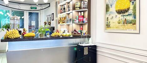 Un espace bar moderne proposant une variété de boissons, une présentation de fruits frais et un tableau décoratif.
