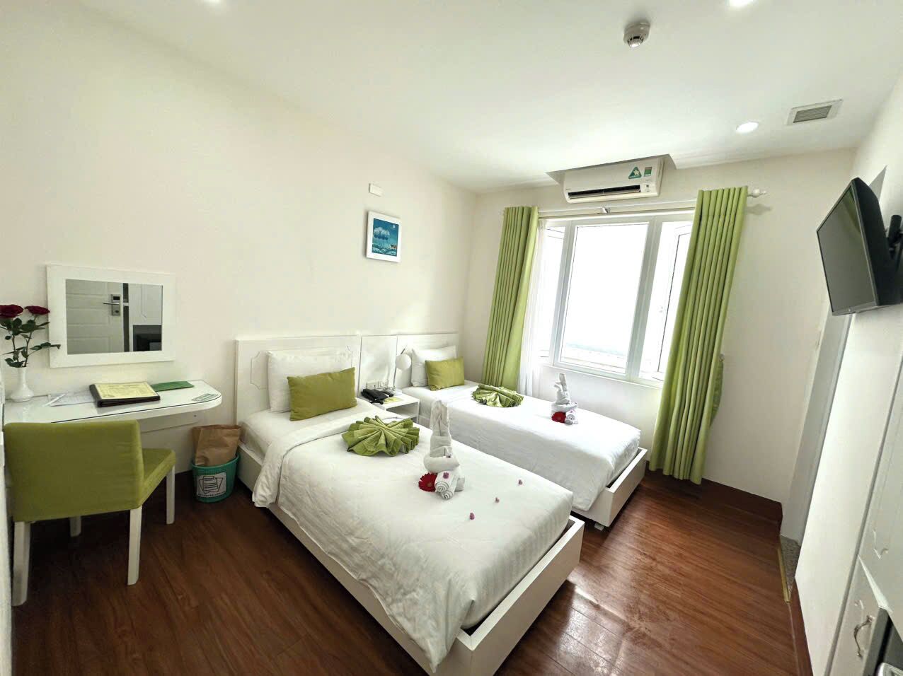 Een hotelkamer met twee bedden, een bureau, een stoel, een televisie en een airconditioning.