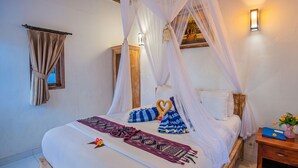 A bed with a canopy, a nightstand with a vase of flowers, and a wall-mounted light. - Svaha Private Villas Ceningan (Ceningan Island)