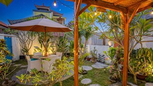 A patio area with a wooden pergola, outdoor seating, and potted plants. - Svaha Private Villas Ceningan (Ceningan Island)