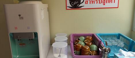 A coffee machine, disposable cups, and a sign indicating a coffee service area.