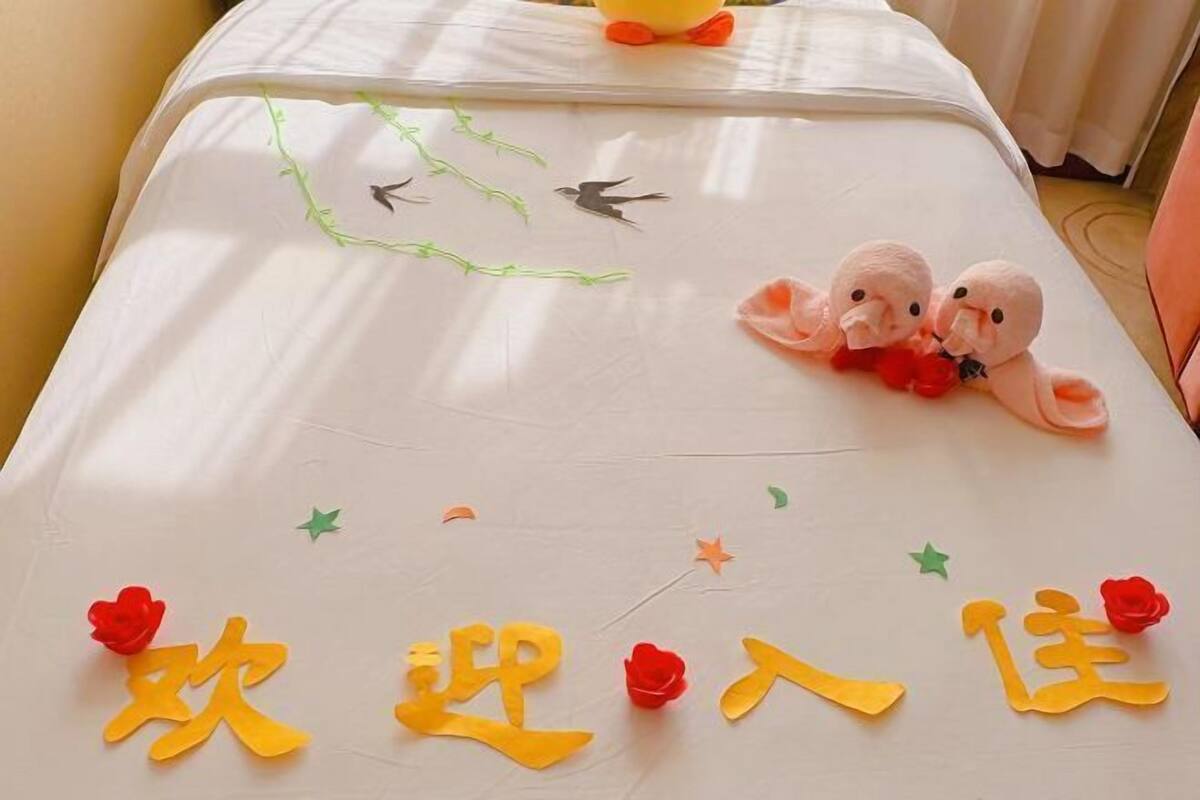 Restful retreat with a bed featuring a colorful bedspread adorned with paper cutouts of birds, ducks, and flowers.
