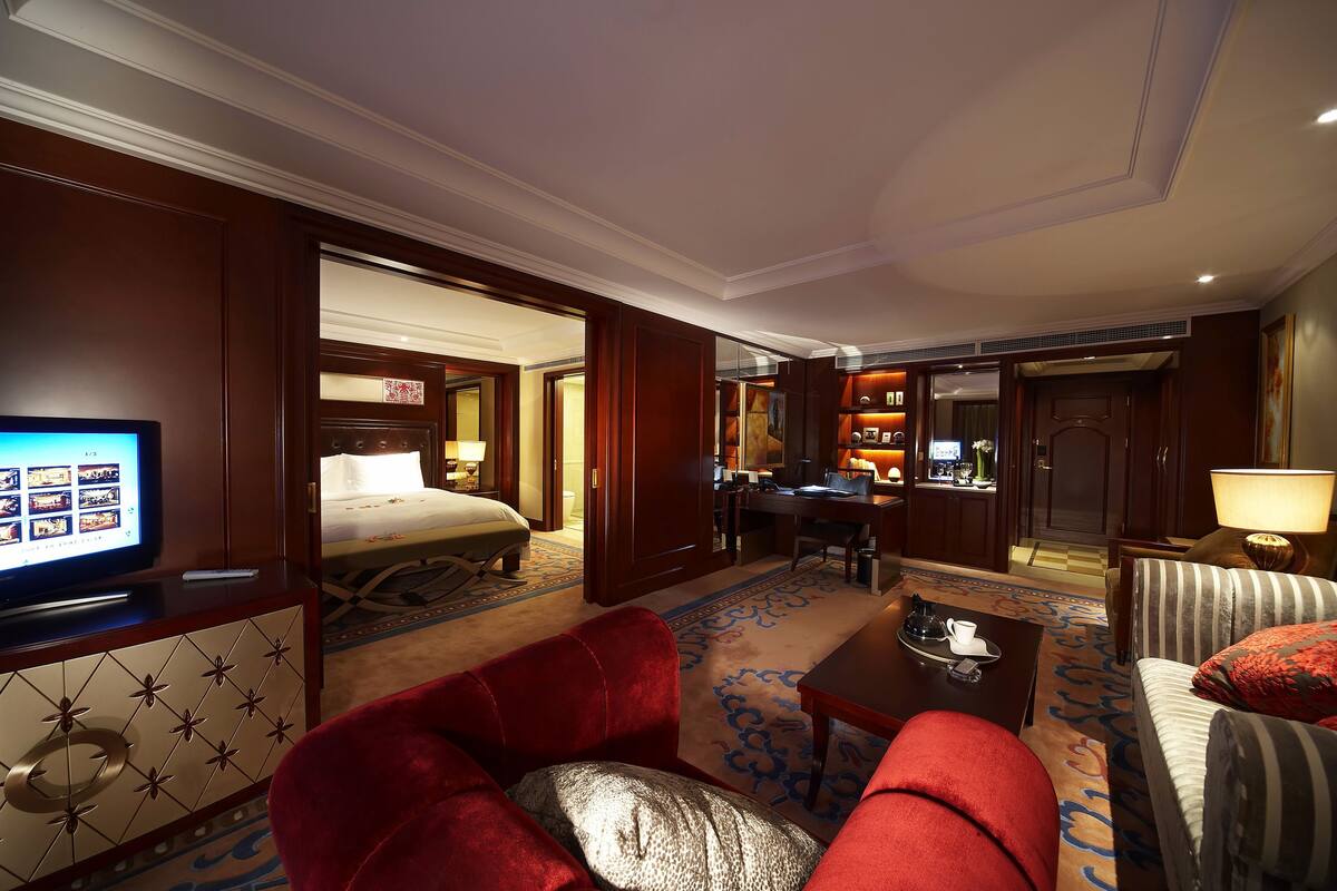Ein Hotelzimmer mit Bett, Schreibtisch, Fernseher und einer Sitzecke mit roten und gestreiften Sofas.