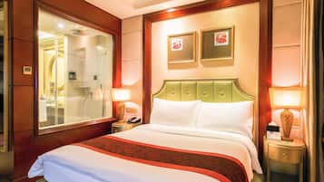 Una habitación de hotel con una cama grande, un espejo, dos cuadros en la pared y una mesita de noche con una lámpara.