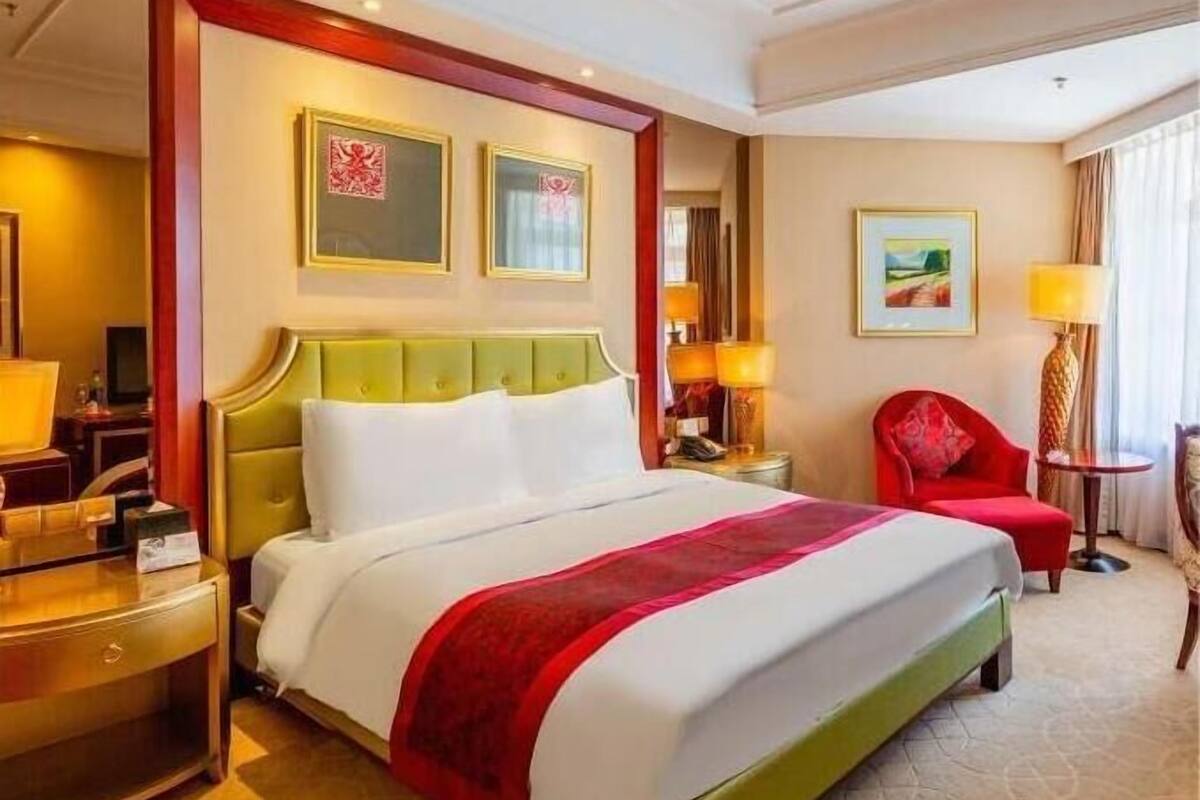 Ein Hotelzimmer mit einem großen Bett, einem Schreibtisch, einem Stuhl und zwei Bildern an der Wand.