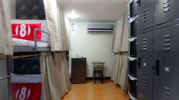 A narrow corridor with bunk beds labeled '18' and '19', a small table, and a refrigerator.