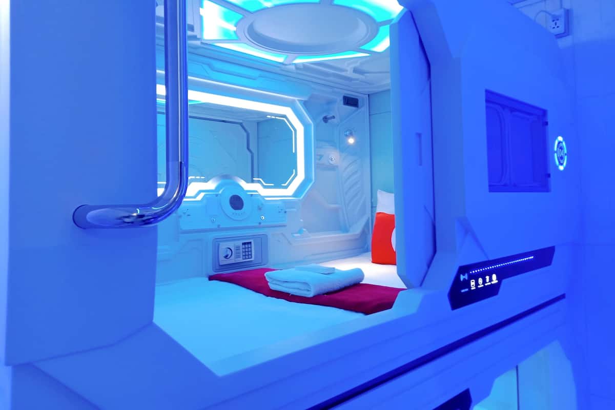 Quarto futurista com cama, painel de controle e janela.