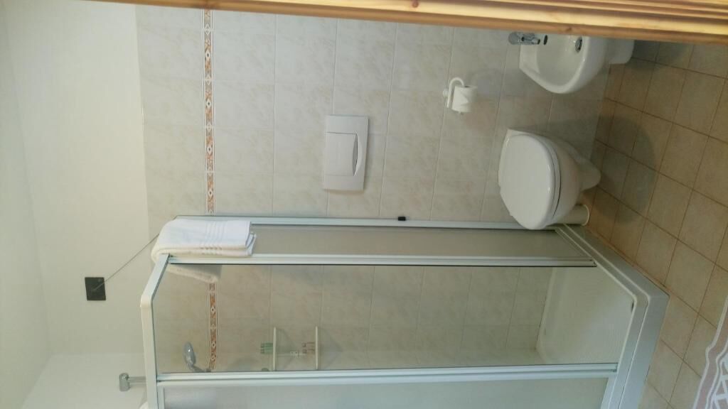 Un baño con cabina de ducha de vidrio, inodoro y lavabo.