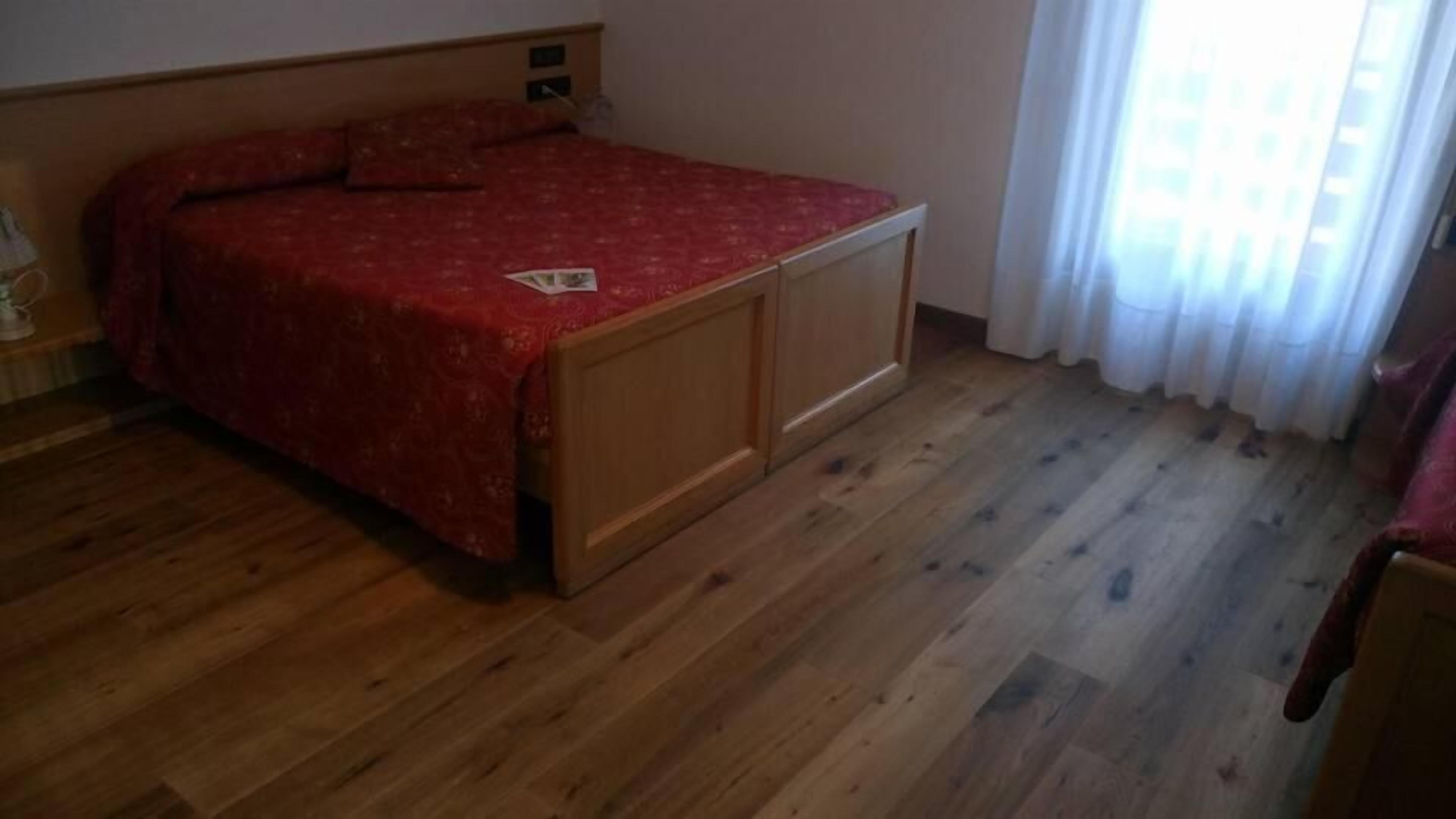 Ein Schlafzimmer mit einem hölzernen Bett, einem Nachttisch und einem Fenster mit Vorhängen.