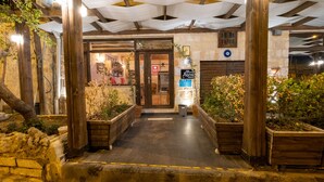 Entrada de un restaurante con fachada de madera, puerta de cristal y un letrero.