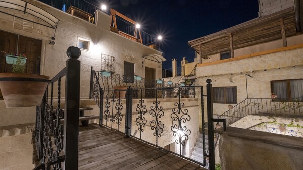 A wooden staircase with ornate black railings leading to a balcony with potted plants.