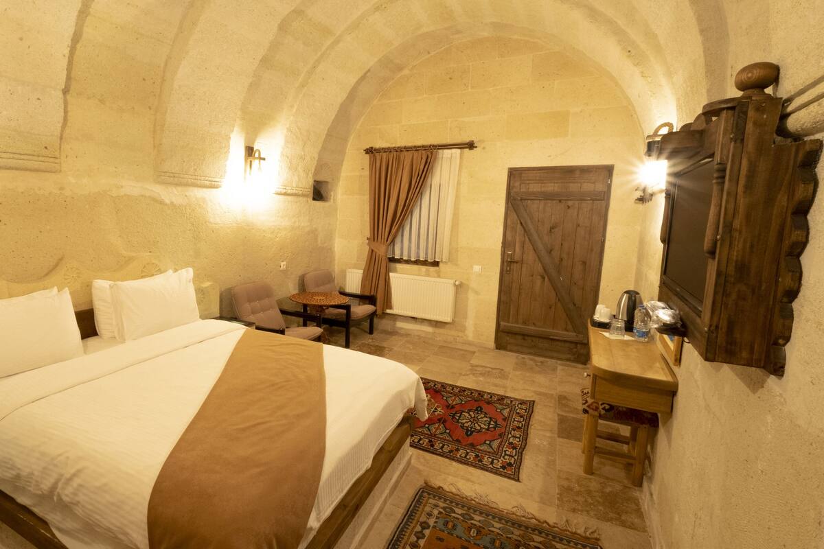 Una habitación con una cama grande, una mesita, una silla y un armario de madera.