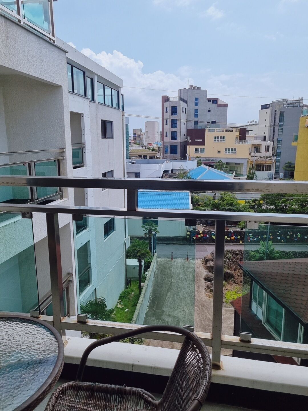 A balcony with a view of a cityscape, including modern buildings and a blue-roofed structure.