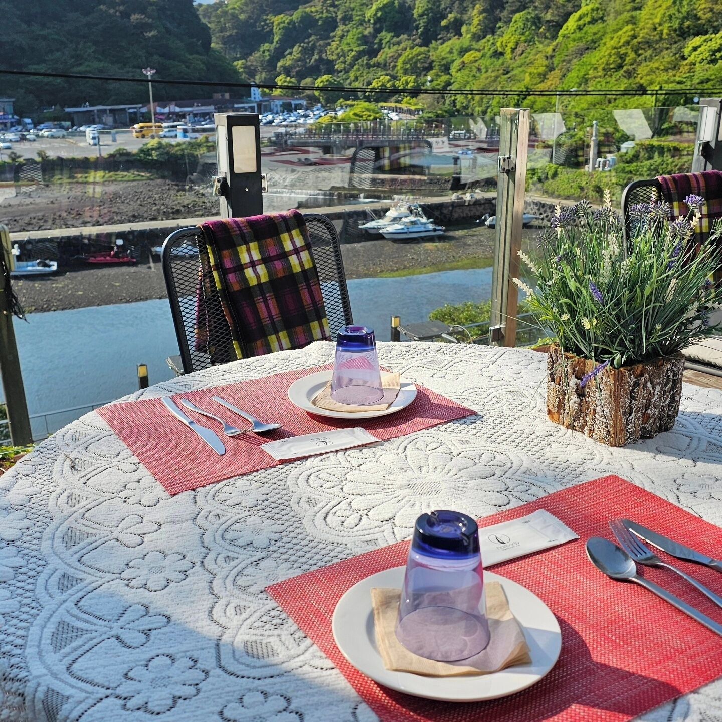 A table set for two with a view of boats and greenery in the background.