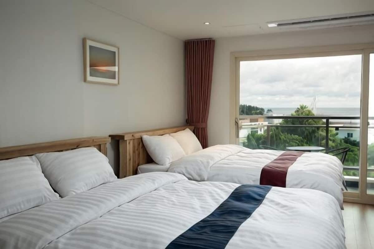 A hotel room with two beds, a large window, and a view of the city.