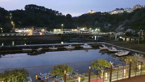 A marina with boats docked, a bridge, and buildings in the background. - Cheonjiyeon Crystal Hotel (Seogwipo)