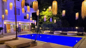 Un área de piscina con sillones de descanso e iluminación colgante.