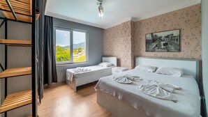 Habitación de hotel con dos camas, una ventana con vistas, un estante de madera y un cuadro colgado en la pared.