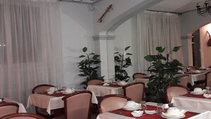A dining area with tables set for service, chairs, and a chandelier. - Hôtel les Troenes (Montpellier)