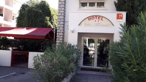 A hotel entrance with a red awning, a sign reading "HOTEL Les Trois Vigneaux," and a glass door. - Hôtel les Troenes (Montpellier)