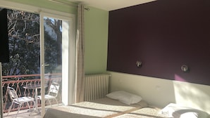 A hotel room with two beds, a balcony with chairs, and a radiator. - Hôtel les Troenes (Montpellier)