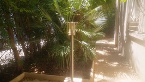 A pathway lined with palm trees and a concrete planter with a light fixture. - Hôtel les Troenes (Montpellier)
