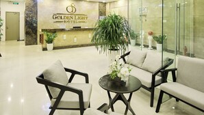 Un vestíbulo de hotel con mostrador de recepción, zona de estar y paredes de vidrio.
