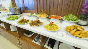 Una mesa de buffet con diversos platos, entre ellos ensaladas, carnes y maíz.