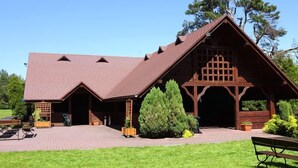 A lodge with a large porch, a covered outdoor seating area, and a well-maintained lawn. - Hotel Ostaniec (Kroczyce)