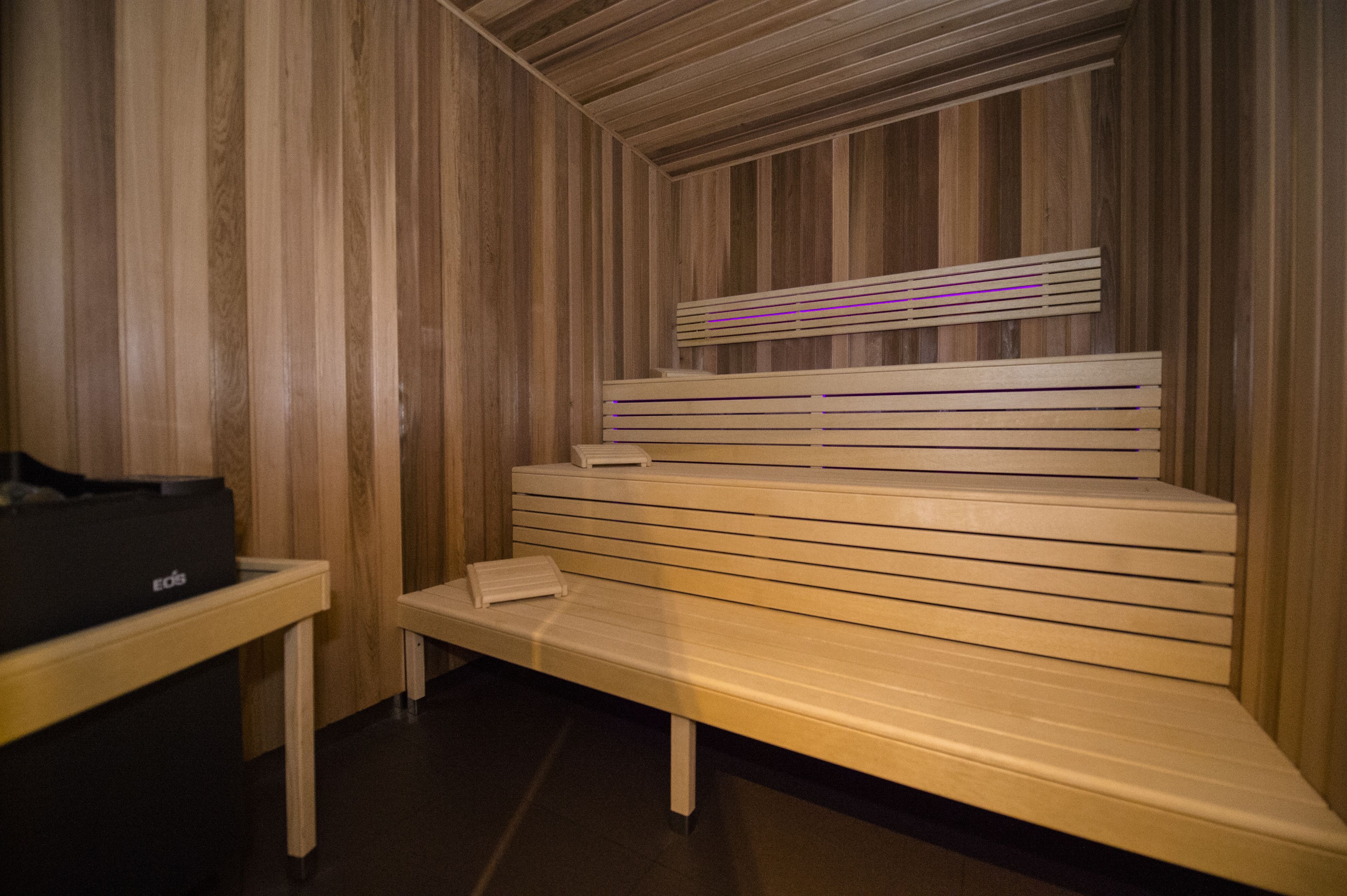 Una sauna con bancos de madera y un banco con una toalla.