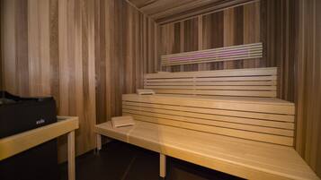 Una sauna con bancos de madera y un banco con una toalla.