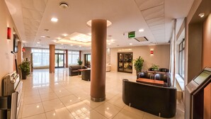 A spacious lobby with a reception desk, seating area, and a large pillar. - Hotel Ostaniec (Kroczyce)