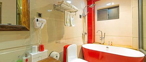 Un baño moderno con una bañera roja, un inodoro blanco y un espejo con marco de madera.