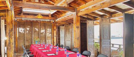 Un salón de conferencias con una larga mesa, sillas y botellas de agua.