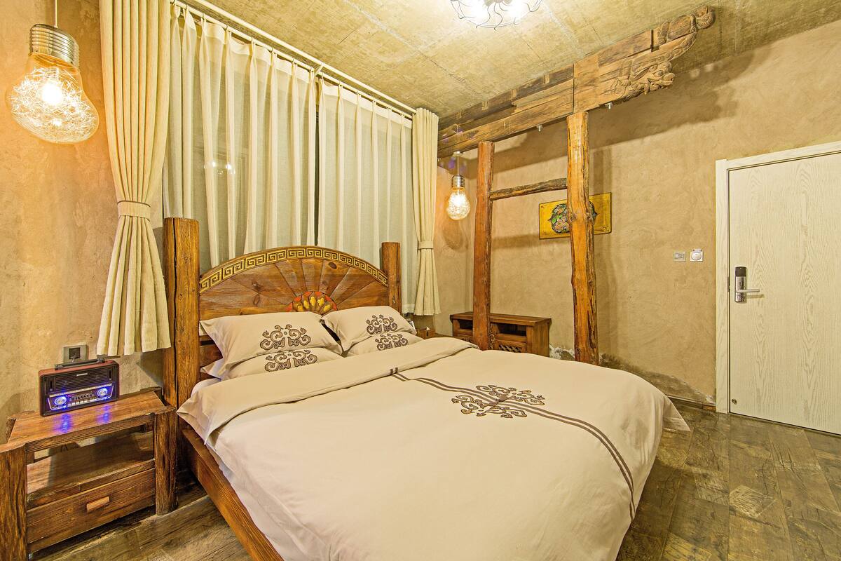 A bedroom with a wooden bed, a nightstand with a radio, and a wooden ceiling.