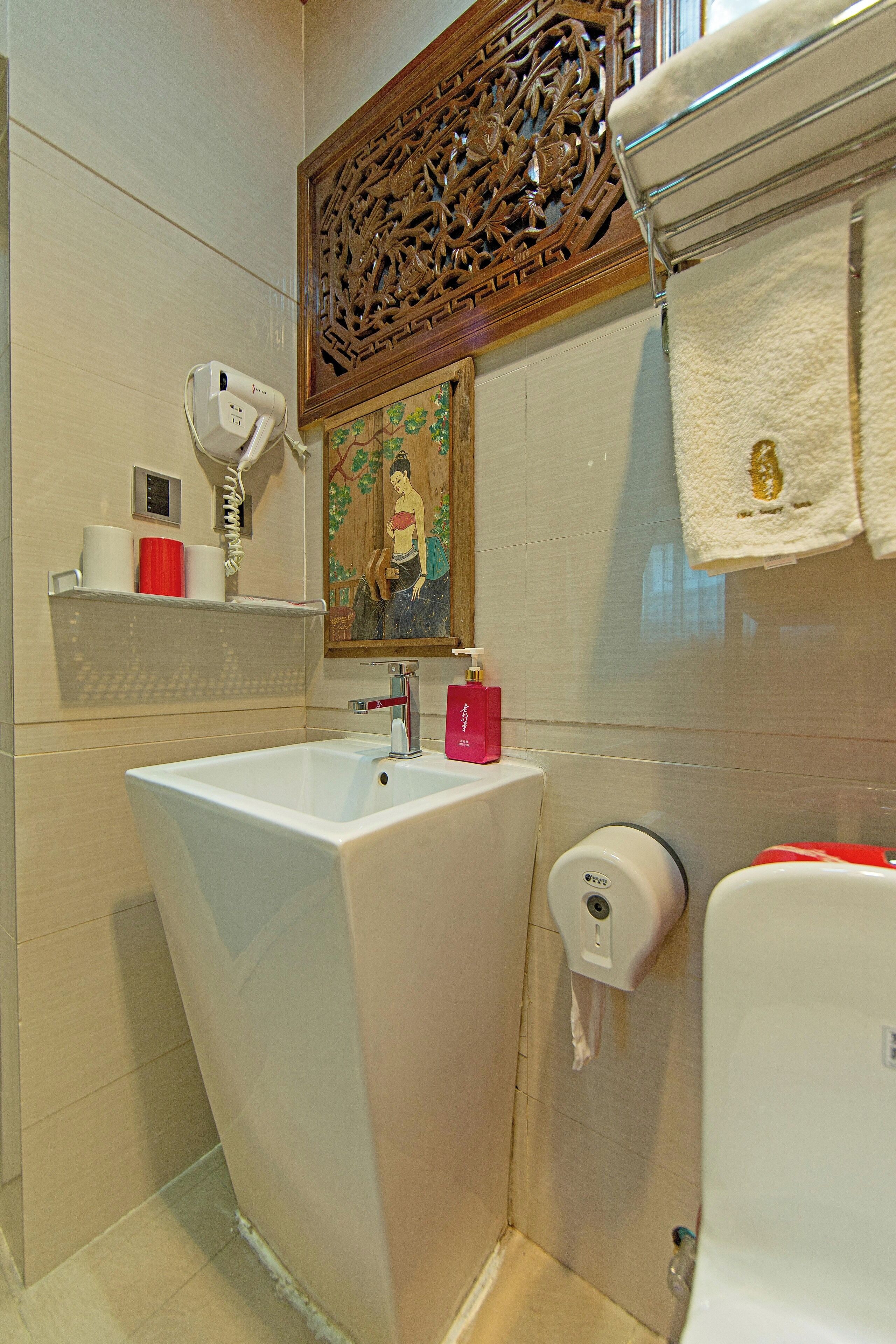 Un baño con un lavabo grande, un secador de manos, dispensador de jabón y un inodoro.