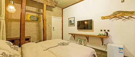 Un dormitorio con cama, escritorio, silla, televisor y refrigerador.