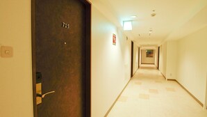 A hotel hallway with a door labeled '715', a light fixture, and a sign on the wall. - Nansei Kanko Hotel (Naha)