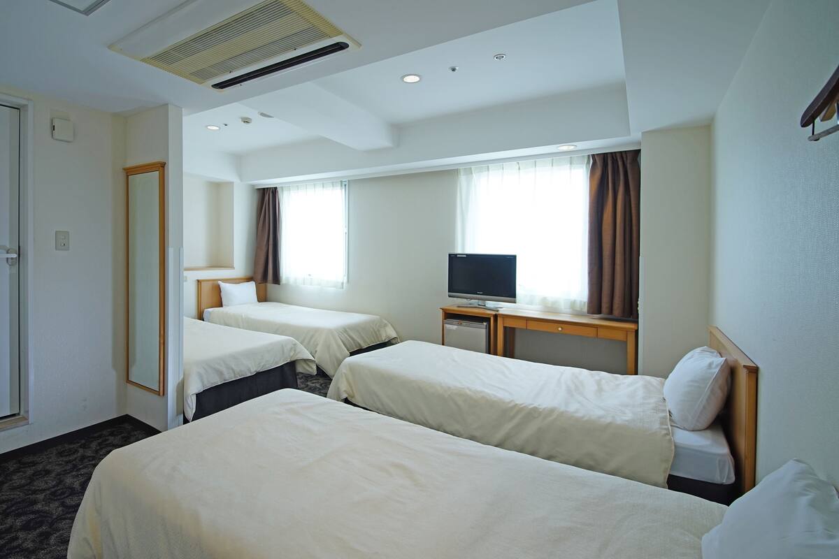 A hotel room with two beds, a television, and a desk.