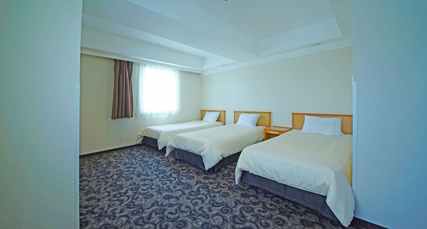 A hotel room with two single beds, a large window with curtains, a patterned carpet, and a simple, clean design.