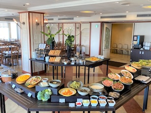A buffet setup with various food items and a seating area with chairs.
