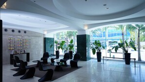 A modern lobby with a curved ceiling, seating area, and large windows offering a view of the street. - Nansei Kanko Hotel (Naha)