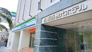 A building with a FamilyMart store on the ground floor, a sign for a hotel, and a staircase leading to the entrance. - Nansei Kanko Hotel (Naha)